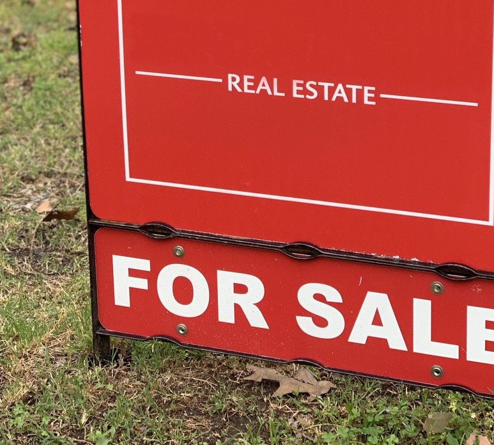 Red Real Estate For Sale sign at a neighborhood home.