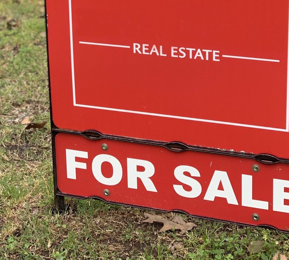 Red Real Estate For Sale sign at a neighborhood home.