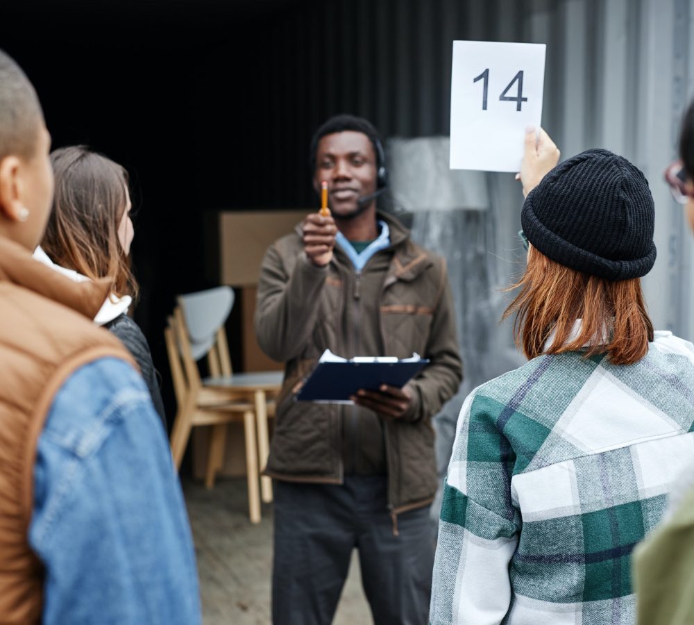 Young woman holding number card at outdoor auction